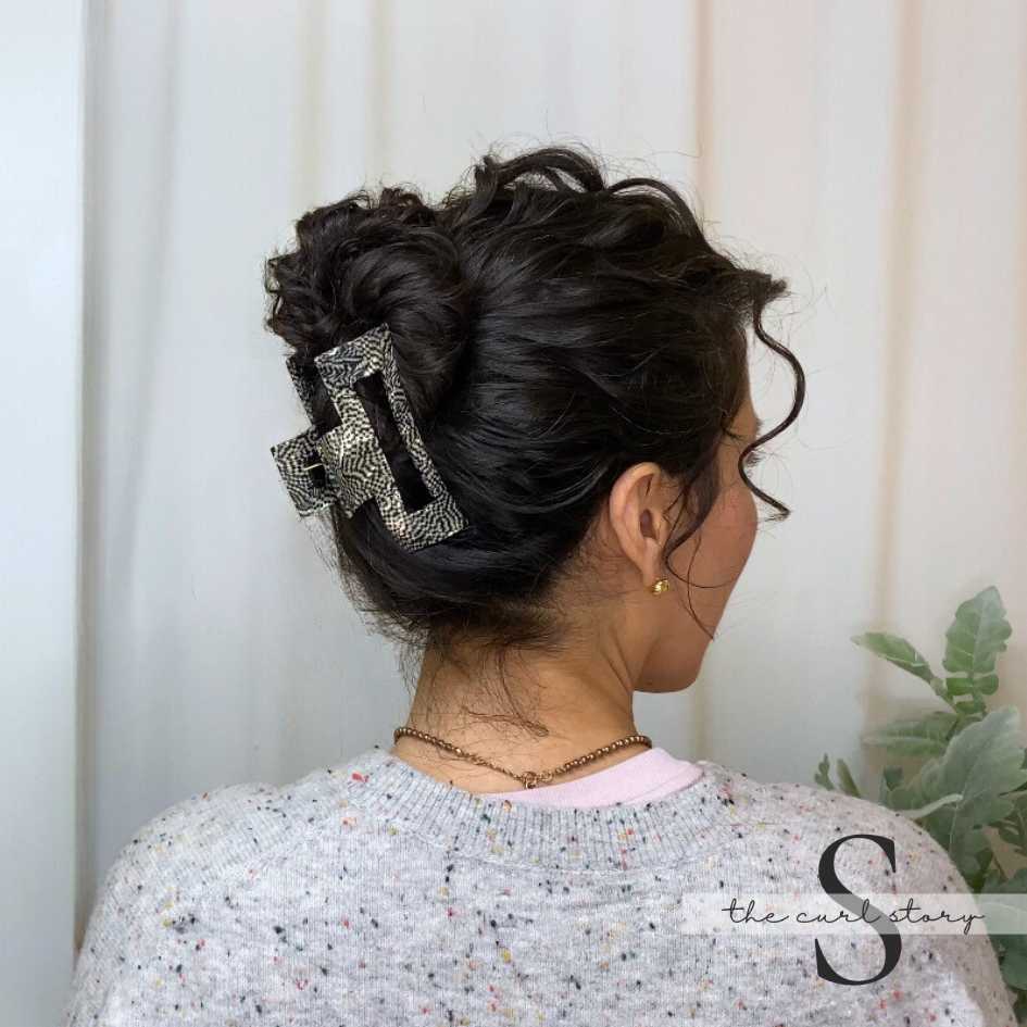 Open Rectangle claw clip holding up a full donut bun on a curly haired brunette
